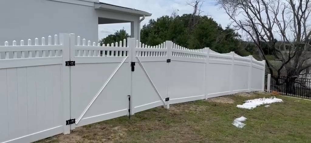 White scalloped vinyl fence with a braced gate